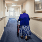 women using a rollator walking down a hallway