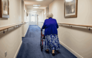 women using a rollator walking down a hallway